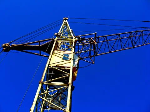 Yellow construction crane on the background of a blue sky Stock Photos
