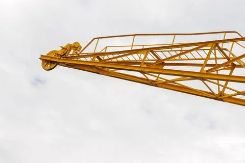 Yellow construction crane boom extending into a cloudy sky with large copy .. Stock Photos