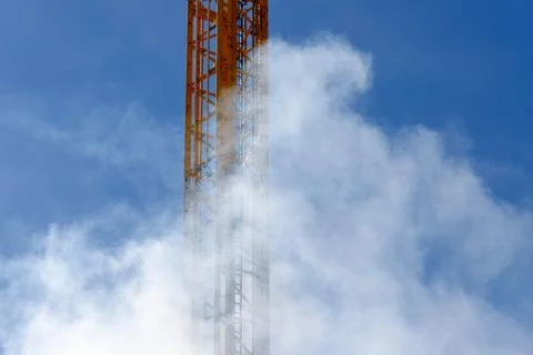 Yellow construction crane disappearing into clouds Stock Photos
