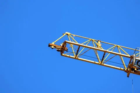 Yellow construction crane operating, blue sky background photo Stock Photos