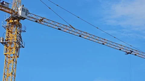 Yellow construction crane tower with horizontal arm against blue sky Stock Footage 297614957