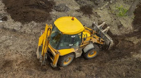 Yellow construction excavator throws the earth onto a flower bed, Stock Photos