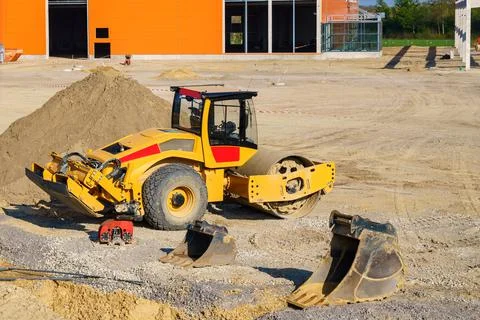 Yellow construction roller on a construction site. Excavator buckets on the g Stock Photos