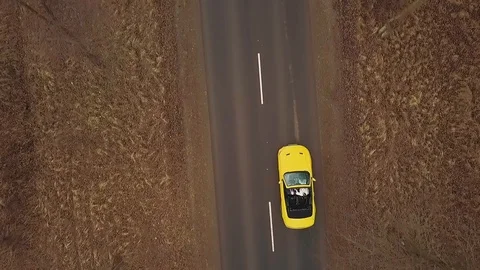 Yellow convertible rides on the road between fields and trees in Autumn. bird's Stock Footage 126174989