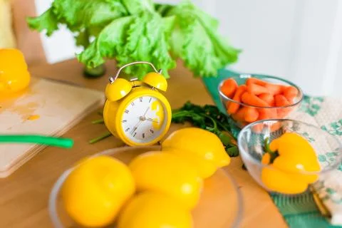 Yellow cooking timer between fresh cooking ingredients - vegetables, lemons a Stock Photos
