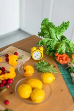 Yellow cooking timer between fresh cooking ingredients - vegetables, lemons a Stock Photos