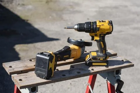 Yellow cordless drill, battery powered impact driver, and angle grinder with  Stock Photos