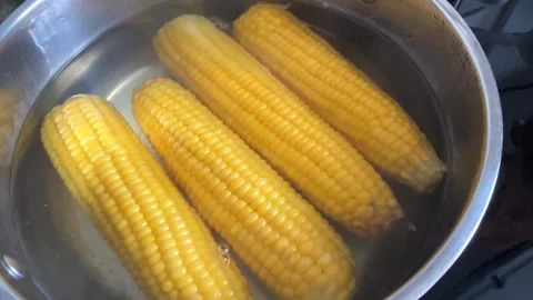 Yellow corn cobs boiling in water in metal pot top view Stockbeeldmateriaal 331529308