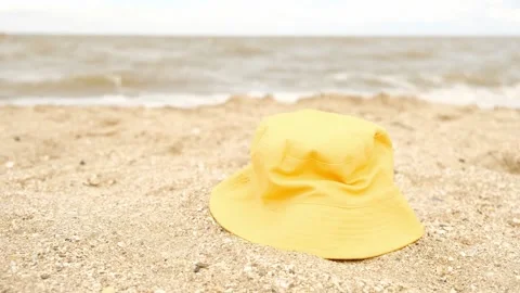 Yellow cotton panama hat on a sandy beach against the background of sea waves. Video stock 201788111