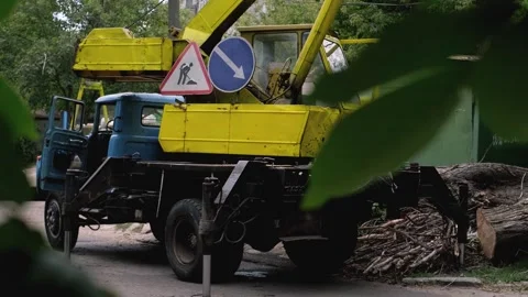 Yellow crane collecting large tree logs, municipal cleanup work after natural di Stock Footage 281577003