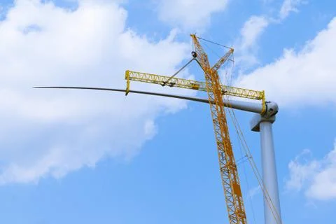 Yellow crane tower placing windmill blade with background of blue sky. Wind T Stock Photos