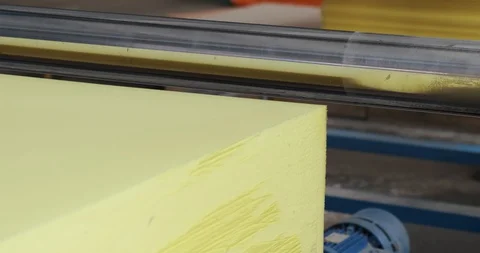 Yellow cube of foam, machine with sharp knife cuts cube into thin sheets of foam Stock Footage 128786711