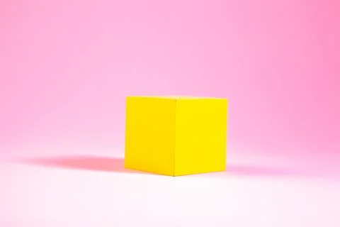 Yellow cube in the shape of a cube on a pink background. Stock Photos