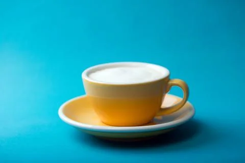 Yellow cup on a blue background Stock Photos