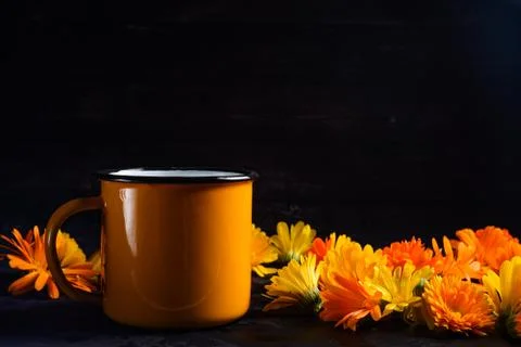Yellow cup of coffee surrounded by yellow dahlias Stock Photos