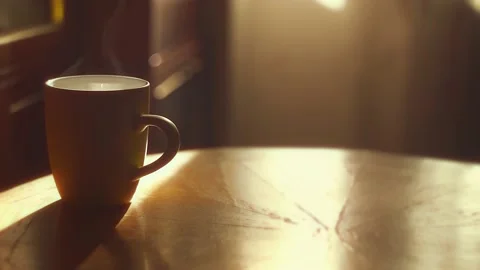 A yellow cup of hot tea surrounded by timid morning sunlight Stock Footage 167692408
