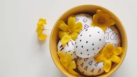 Yellow cup on a white background with Easter eggs. female hand pulls one egg out Stock-Footage 108197118