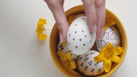 Yellow cup on a white background with Easter eggs. female hand puts one egg in a Stock-Footage 108197138