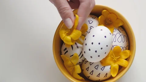 Yellow cup on a white background with Easter eggs. Female hand puts a yellow 스톡 동영상 108197159