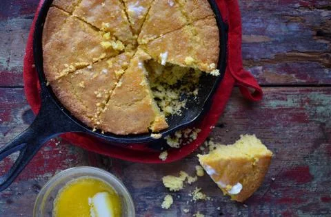 Yellow cut cornbread with removed piece in cast iron Stock Photos