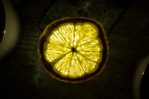 Yellow cut lemon in the light lying on the table Stock Photos