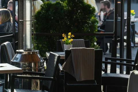 Yellow daffodils in a ceramic pot on the table of a street cafe illuminated Stock Photos