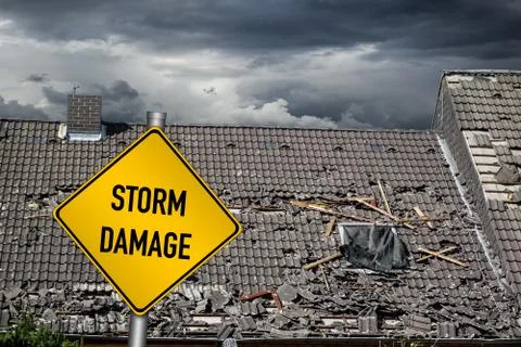 Yellow damage warning sign in front of storm damaged roof of house Stock Photos