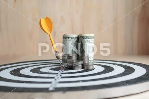 Yellow dart arrow hit the center target of dartboard and money coin metaphor Stock Photos