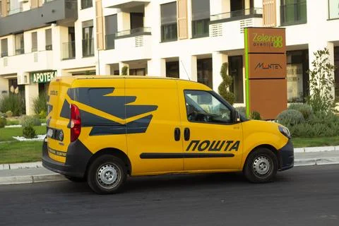 Yellow delivery van with Cyrillic Post lettering parked on city street Stock Photos