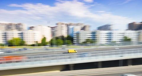 Yellow delivery van in rush, motion blur effect, panoramic city view Фото
