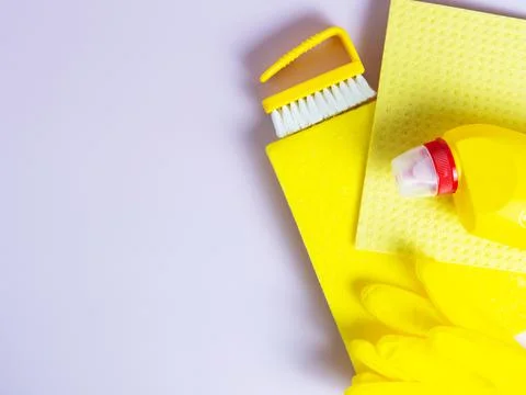 Yellow detergent bottle with sponge on folded yellow napkin and yellow rubber Stock Photos