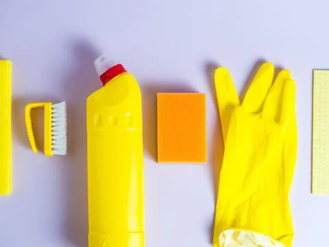 Yellow detergent bottle with sponge on folded yellow napkin and yellow rubber Stock Photos