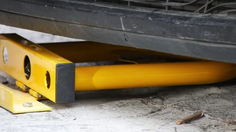 Yellow device blocks vehicle from moving on pavement Stock Footage 309358514