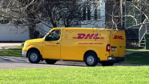 A yellow DHL Express delivery van on a residential street during a daytime Stock Footage 335585147