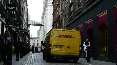 Yellow DHL van driven on a narrow London street Stock Footage 10716694
