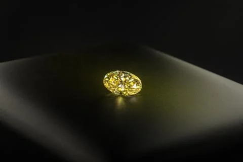 A yellow diamond is on a black surface Stock Photos