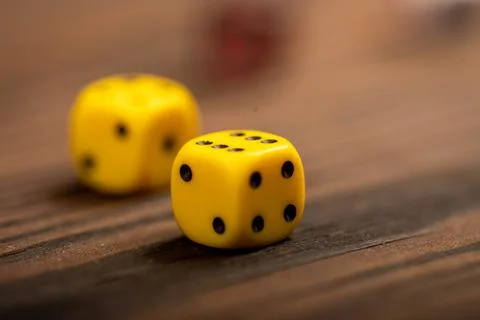 Yellow dice scattered on a wooden table. Close-up, selective focus. Stock Photos