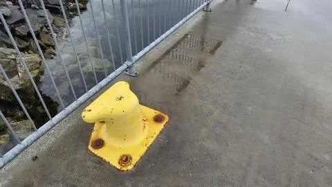 Yellow dock post stands on a wet pier near water in a quiet location Fotos Stock