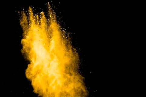 Yellow dust particles explosion on black background.Yellow powder dust splash Stock Photos