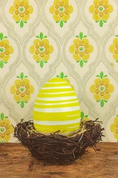 Yellow dyed big easter egg in a bird nest on a wooden table Foto stock