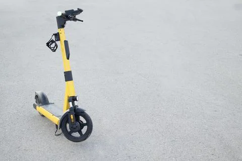 Yellow e-scooter side view on wet asphalt Stock Photos