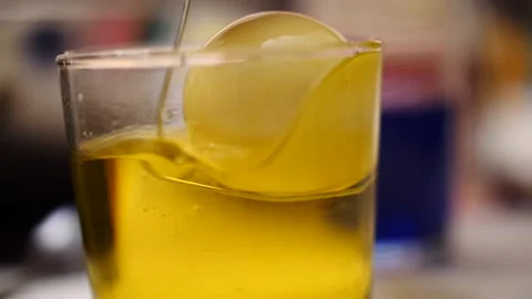 Yellow Easter egg being pulled out glass full of yellow dye colorful slow motion Stock Footage 151502552