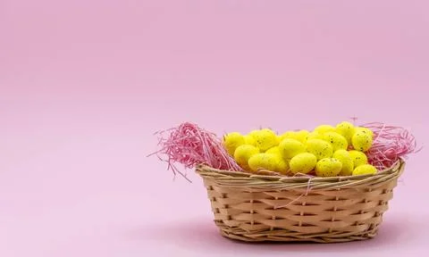 Yellow Easter Egg with freckles pattern inside a basket on Pink Background 스톡 사진