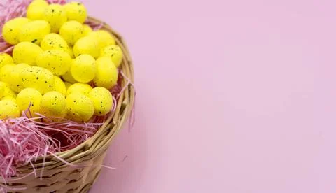 Yellow Easter Egg with freckles pattern inside a basket on Pink Background Stock Photos