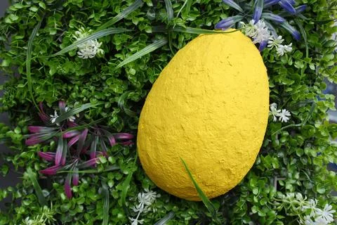 Yellow Easter egg resting in a lush green garden setting decoration Стоковые фото