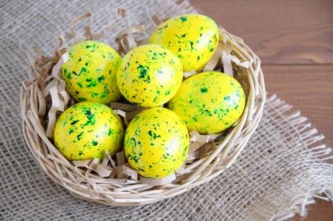 Yellow Easter eggs in a basket. On linen fabric brown. Wooden brown backgroun Stock Photos