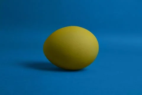 Yellow egg on blue background Stock Photos