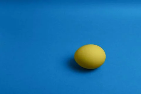 Yellow egg on blue background Stock Photos