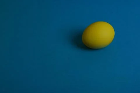 Yellow egg on blue background Stock Photos