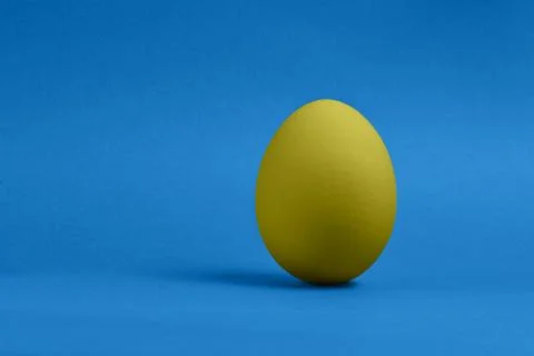 Yellow egg on blue background Stock Photos